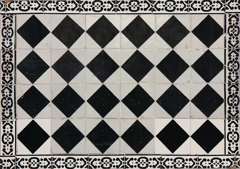 Sol en carreaux noirs et blancs posés en losange, encadré d’une frise