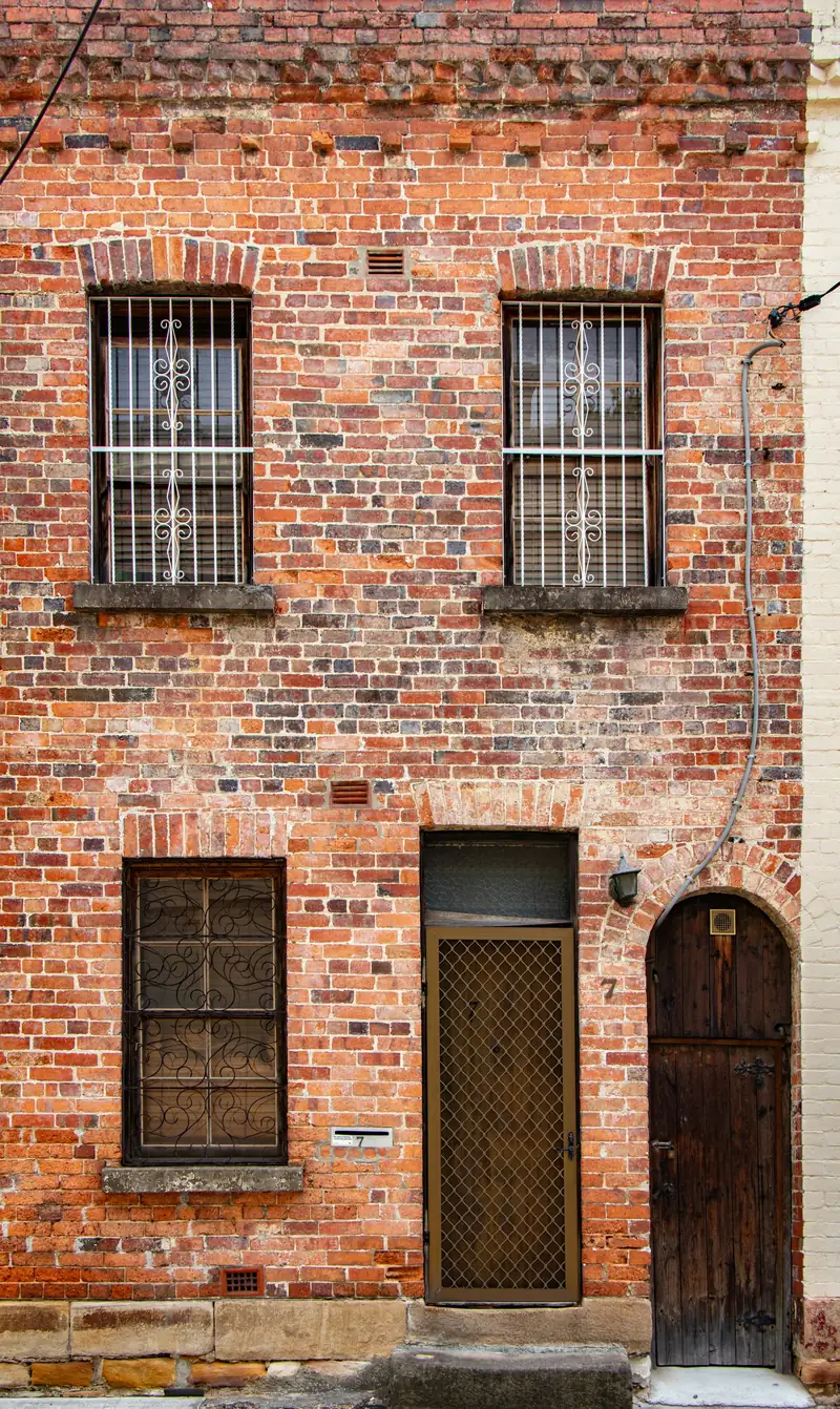 Étroite maison de ville en brique, fenêtres à barreaux et porte cintrée