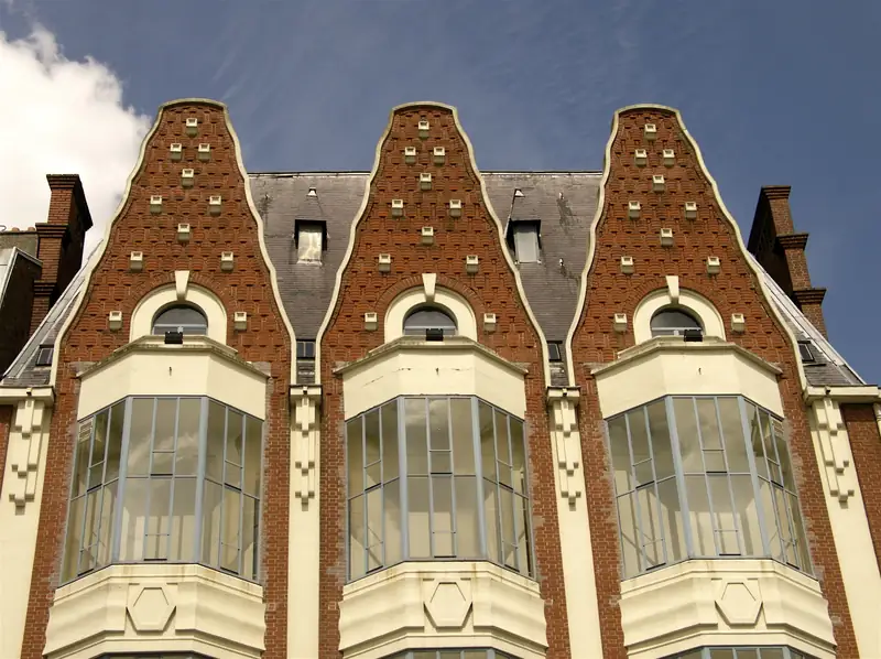 Trois pignons de brique rouge à décor de losanges, au-dessus de bow-windows