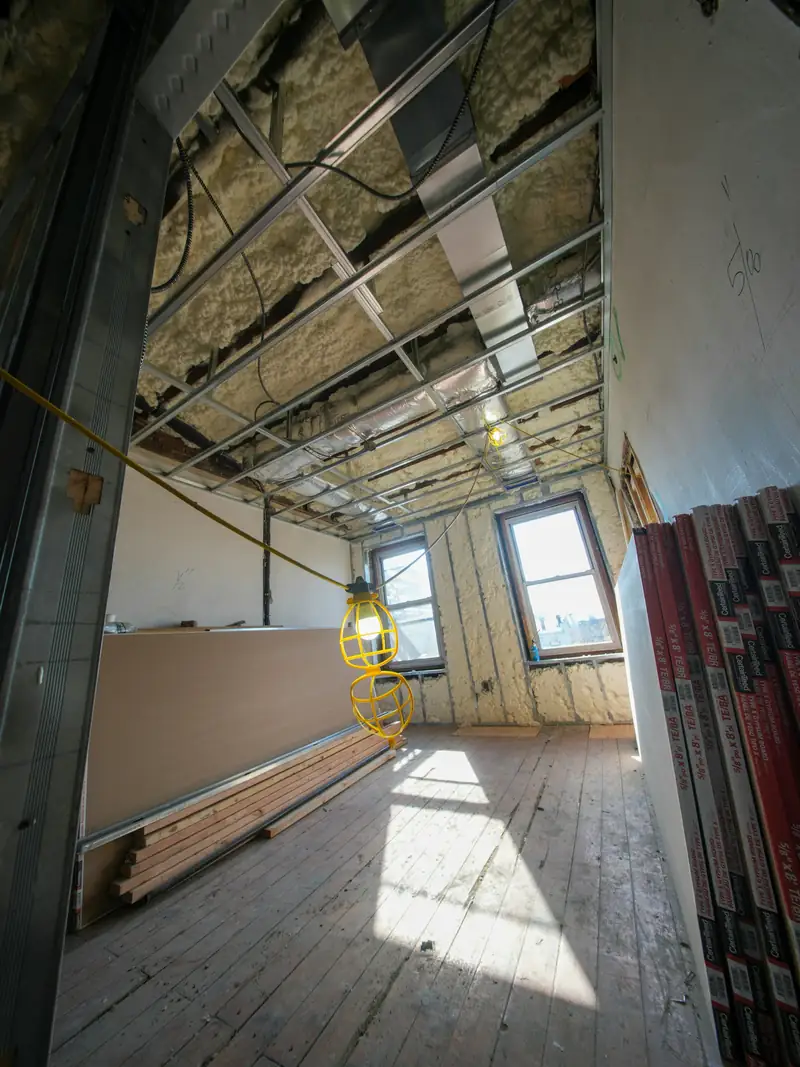 Pièce lumineuse en chantier : plafond ouvert sur ses rails et plaques prêtes à poser