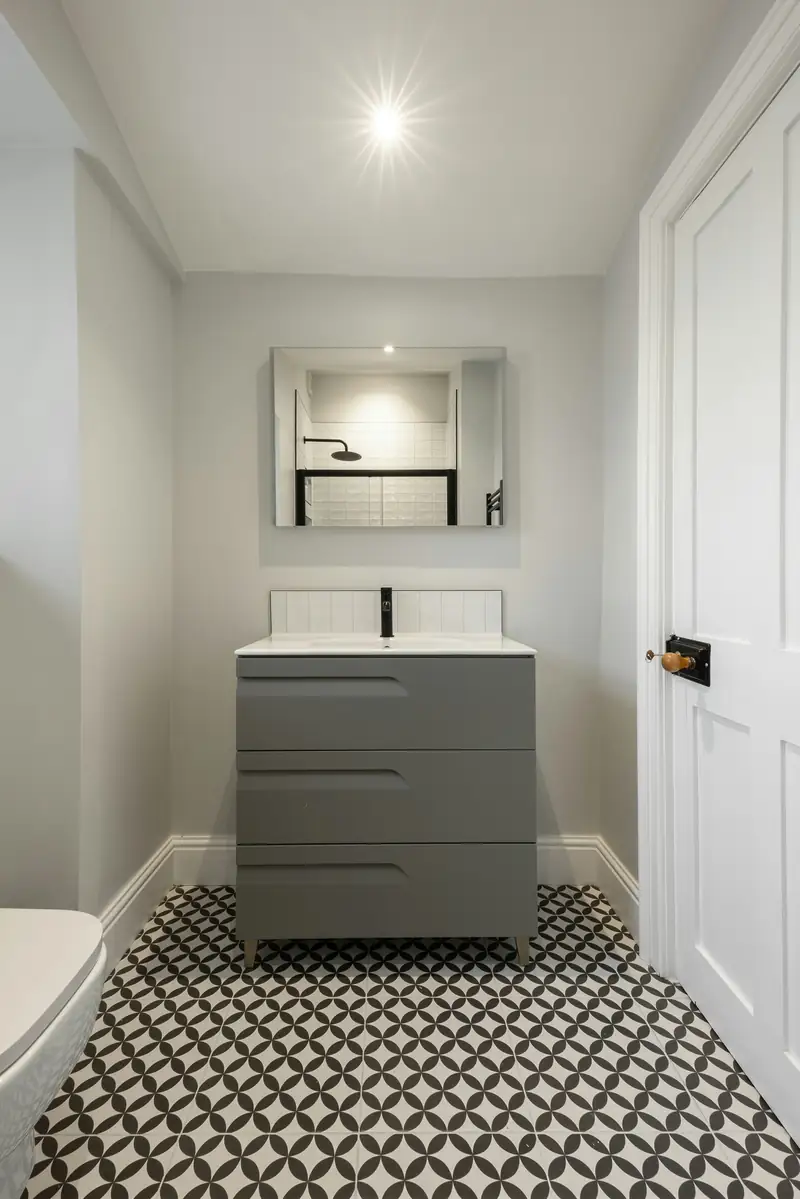 Petite salle de bain claire, meuble gris et sol en carreaux à motif noir et blanc